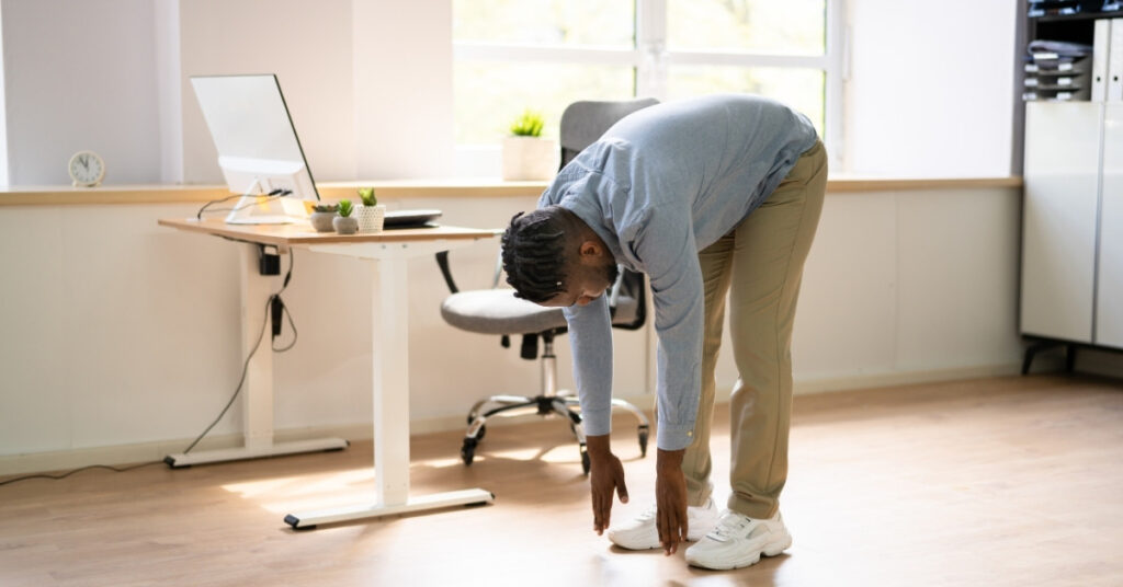 Trabajador realizando estiramientos en la oficina para mantener una buena ergonomía